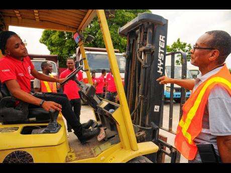 Patrick Pottinger (right), instructor, gives pointers to trainee Rushawn Williams during forklift operator training at Thompson’s Trucking and Equipment on Waltham Park Road yesterday.