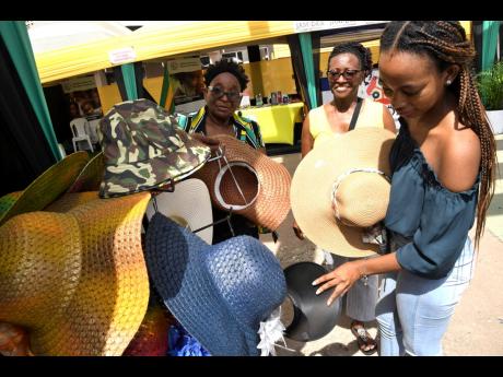 Credit: Rudolph Brown Tatti Robertson (left), owner of Tatonis Accessories Plus, shows her hats to Saffron Fletcher (right), and Juliet M Brown at Augus Morning Market.
