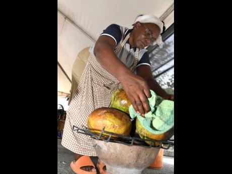 Credit: Rudolph Brown Jennifer Mais roasts breadfruit at Augus Morning Market at the Emancipation Village at the National Arena in Kingston yesterday.