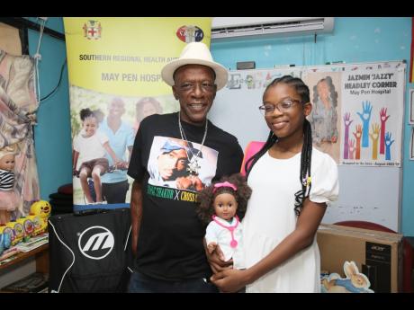 Jazmin Headley and her uncle Rohan Myers hand over computers, books and other items to the Paediatric Ward at the May Pen Hospital.