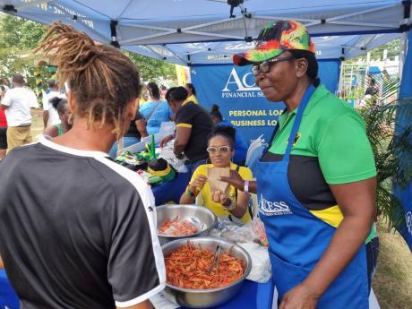 Shrimp vendor and customer of Access Financial Services (AFS) Beverley ‘Miss Bev’ Bailey (right) tends to a patron at the AFS booth on Black River Day on July 28.