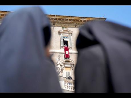 Credit: AP Andrew Medichini Nuns look at Pope Francis as he recites the Angelus noon prayer from the window of his studio overlooking St.Peter’s Square, at the Vatican, on Sunday, August 20.