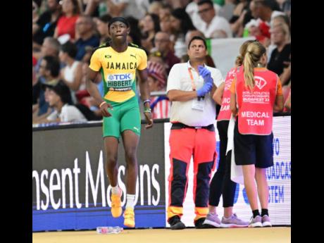 Medical team members check with Jaydon Hibbert following his first attempt in the men’s triple jump final. Hibbert exited the competition without registering a jump because of a hamstring injury.