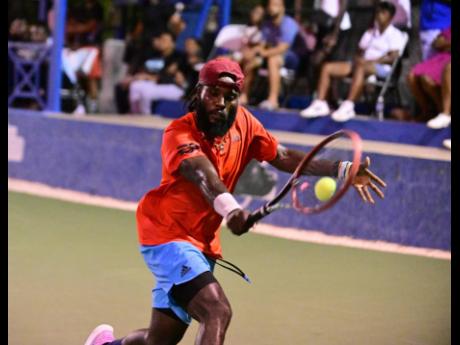 Credit: Gladstone Taylor Jeremy Miller stretches to play a backhand shot in the men’s open final against David Goldsmith at the Innovative Invitational Amateur Tennis Classic at Liguanea Club in June. Miller won 2-1.