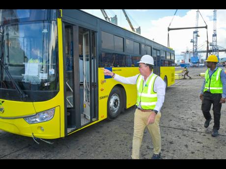 Minister of Science, Energy, Telecommunications and Transport  Daryl Vaz (left) inspects one of 50 new buses which arrived in the island last Friday.