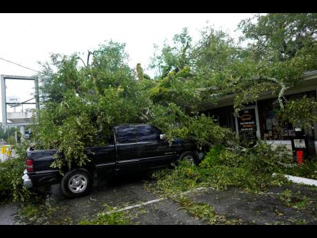 A fallen tree lies atop the Mayo Cafe and a truck parked outside in Mayo, Florida.