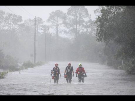 Rescue workers with Tidewater Disaster Response wade through a tidal surge on SW 358 Highway while looking for people in need of help after the Steinhatchee River flooded in Steinhatchee, Florida.