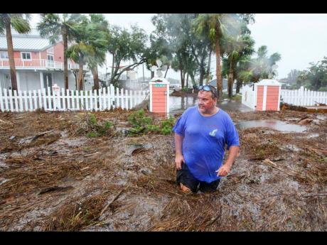 Daniel Dickert wades through water in front of his home, where the Steinhatchee River overflowed in Steinhatchee, Florida.