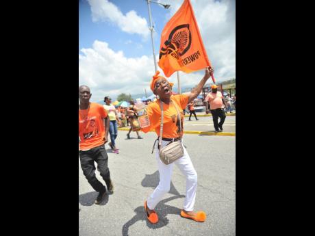 A Patrick Peterkin supporter carries her PNP flag even as she hopes he will deliver St Andrew East Rural for the party.