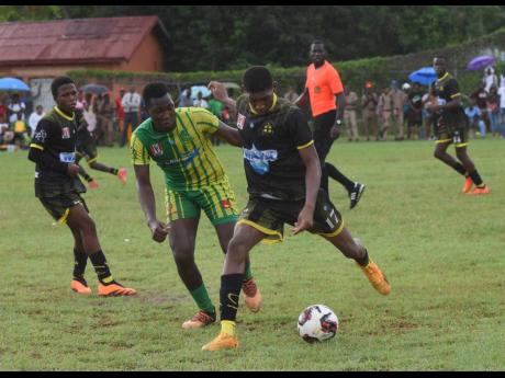 Petersfield High School’s Leo Nesbeth (centre) battles with Black River High’s Adrian Johnson during the ISSA/daCosta Cup match at the Petersfield Sports Complex yesterday. Black River won 1-0