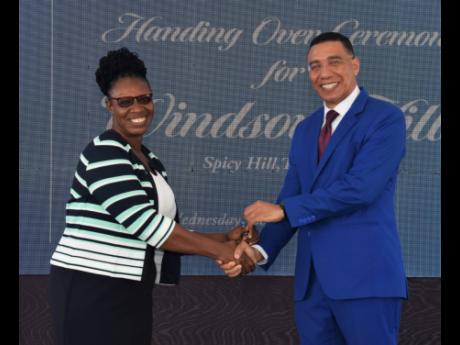 Tricia Hylton collects the key to her house from Prime Minister Andrew Holness.