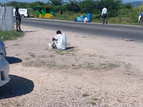 A relative of the deceased couple sits dejectedly as investigators comb the scene. 