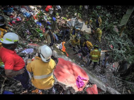 Fire personnel and residents of Bowden Hill in St Andrew dig through the collapsed building in hopes of finding Baby Timera alive.