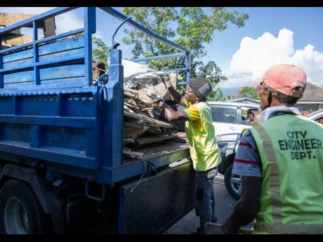 Kingston and St Andrew Municipal Corporation workers move debris from stalls at ‘Crab Circle’. 