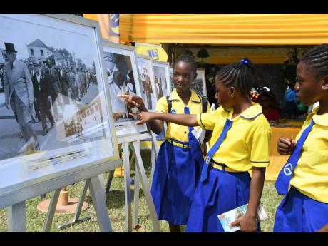 Grade-six students of Keith Primary and Infant School in St Ann look at a historic photograph displayed by the Jamaica Information Service during the 24th staging of the Seville Heritage Expo, held at the Seville Heritage Park in St Ann.