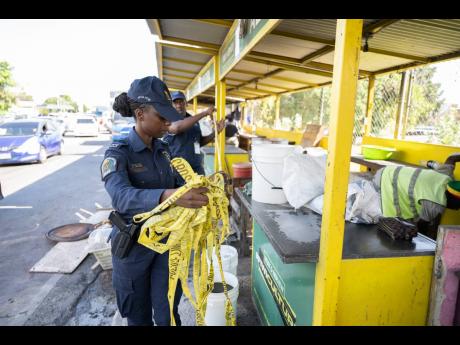 Members of the Jamaica Constabulary Force cordon the popular Crab Circle food spot in Kingston last Thursday after a visit by health officials.
