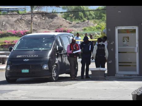 Police investigators process the scene where armed robbers attacked Beryllium security personnel as they were servicing an ATM in the Harbour View Shopping Centre, St Andrew, yesterday.