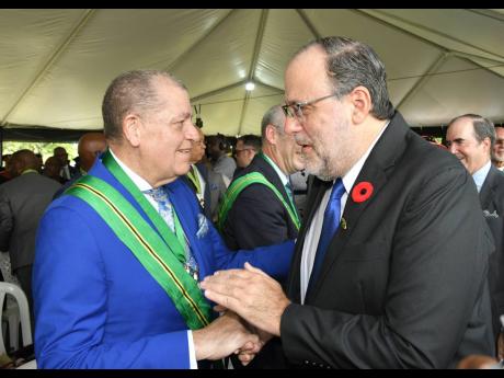 Leader of the Opposition Mark Golding (right) congratulates recipient of the Order of Jamaica (OJ), Member of Parliament for Manchester North Eastern, Audley Shaw, during the Ceremony of Investiture and Presentation of National Honours and Awards, held on the lawns of King’s House yesterday.