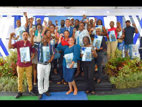 Prime Minister Andrew Holness (centre) is surrounded by new homeowners of the Shrewsbury Housing Development phase two, in Petersfield, Westmoreland, following a National Housing Trust handover ceremony on Wednesday.