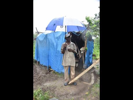 Credit: Nicholas Nunes Eighty-three-year-old Harold Moore stands in front of his humble abode in the middle of a field in Ferry, St Andrew.