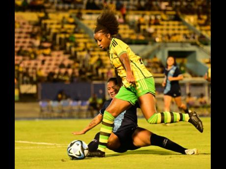 Reggae Girl Mikayla Dayes (right) goes past Guatemala’s Vivian Montenegro during their Concacaf Women’s Gold Cup qualifying match at the National Stadium last night. The match drew 2-2.