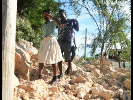 Residents walk over the rubble after a massive landslide blocked the entrance to the community of Melbrook Heights, Harbour View, St Andrew.