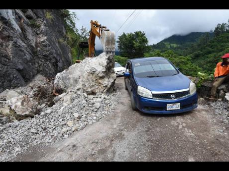 Motorists navigate around a huge boulder in the Woodford area. Some have had to park their vehicles at a particular spot and take taxis in order to get home.