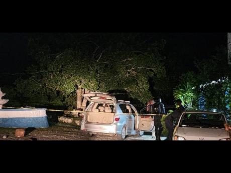 Police inspect the taxi that was shot up in Flower Hill, St James, killing three people, including two schoolboys.