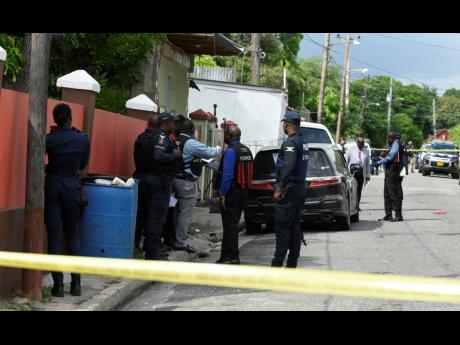 Credit: Kenyon Hemans Police process the crime scene in the Dunkirk community of east Kingston yesterday.