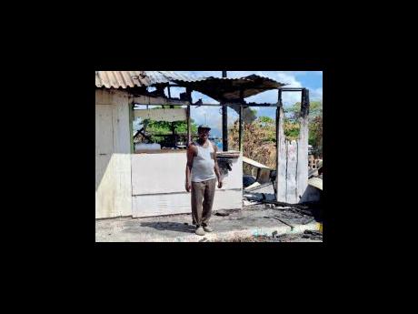 Clifton Carr stands in front of his burnt-out shop at the Port Henderson Fishing Village in Portmore, St Catherine, yesterday.