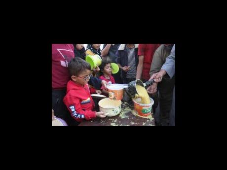 Palestinians line up for food, during the ongoing Israeli bombardment of the Gaza Strip, in Rafah on Monday.