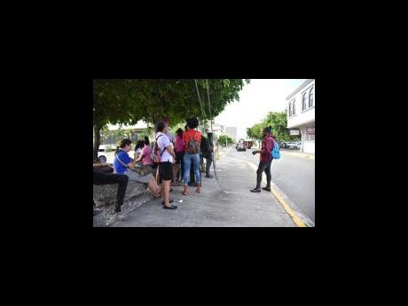 The work day came to a halt for businesses inside the New Kingston Business Centre yesterday after a bomb threat was reported about 10 a.m. Employees of the various entities wait for security personnel to complete a search.