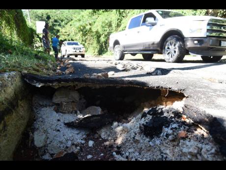 Motorists make their way along the Chancery Hall main road in St Andrew which was severely damaged by heavy rains.