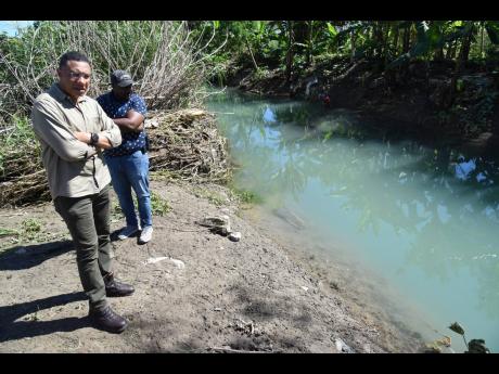 Prime Minister Andrew Holness looks at a section of the Plantain Garden River that overflowed its banks and flooded farms in Golden Grove, St Thomas. Farmerrs suffered millions of dollars in losses due to floodwaters that covered the fields for more than two days.