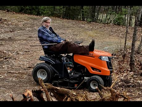 In this photo provided by Ed Smith, Geoffrey Holt rests his leg on top of his riding mower.