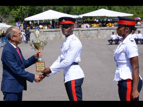 Minister of National Security Dr Horace Chang (left) presents Constable Kenneil Datadeen with the trophy for obtaining the highest marks, during the passing-out parade for 290 new Jamaica Constabulary Force constables. The event was held on Wednesday at the National Police College of Jamaica in Twickenham Park, St Catherine. Looking on is Woman Constable Zennesah Francis, who was the joint recipient for attaining the highest marks.