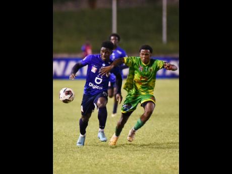 Excelsior’s Nathaniel Watson (right) and  Jamaica College’s (JC) Jamoy Dennis battle for the ball during their ISSA/Walker Cup schoolboy football knockout semi-final match at Stadium East yesterday. JC won 3-0.
