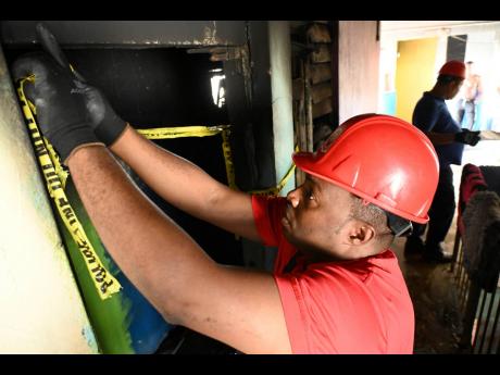 Credit: Rudolph Brown Photos Members of the Jamaica Fire Brigade investigate what caused the blaze that claimed the life of 80-year-old Claudia McNeish.