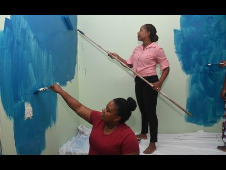 Tracey Ann Davis (left), assistant administrator at Mustard Seed Communities’ Mary’s Child, gets down to business, joining Nadine Reid-Berry, IGT administrative assistant, in a painting session during the festive Christmas Treat held on December 7.