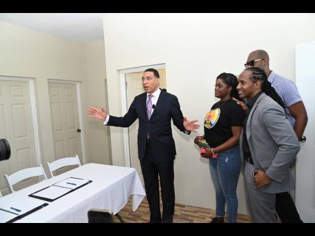 Prime Minister Andrew Holness (left) gets a tour of Shaneil Francis’ new home in St Catherine. Looking on are Alando Terrelonge (right), member of parliament for St Catherine East Central and state minister in the Ministry of Foreign Affairs and Foreign Trade; and Robert Miller, member of parliament for St Catherine South Eastern.