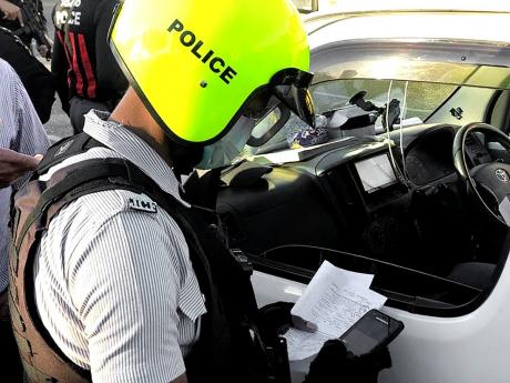 A policeman utilising the e-ticketing system to check a motorist’s car documents.