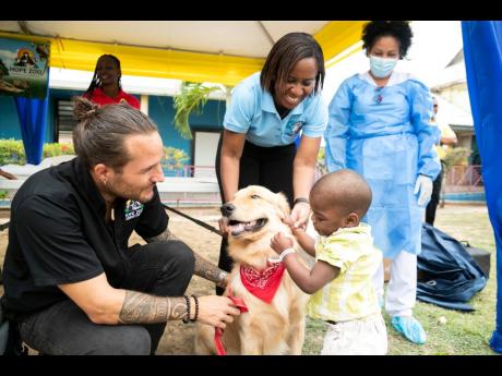 Young Leo Irving,  a patient at the Bustamante Hospital for Children, pets therapy dog Dr Teddy Barks  at the hospital. Looking on are (from left) Joey Brown, curator for the Hope Zoo;  ENT consultant Dr Marsha James;  and Nurse Yohima Barban Lao from the hospital’s Intensive Care Unit. 