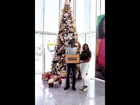 Ralph Bascoe, grand prize winner of Digicel’s ‘Christmas is a 10’ promotion, is presented with a brand new laptop for his daughter’s studies by Kimberley Campbell, head of business marketing at Digicel. 