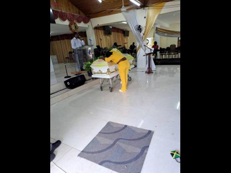 Dahlia Blackwood leans over on the coffin bearing the remains of her father, Steven.