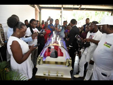 Mourners try to get pictures and videos of Robert Lee Malcolm, more popularly known as Gully Bop, at his thanksgiving service held at the Ranny Williams Entertainment Centre yesterday.
