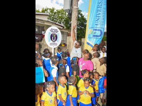 Minister with responsibility for Information and Member of Parliament for Clarendon North Central, Robert Morgan (centre, back row), celebrates the launch of the Universal Service Fund’s free, secured Wi-Fi service in Beckford Kraal, Clarendon, with students from the community. The Wi-Fi was unveiled last week.