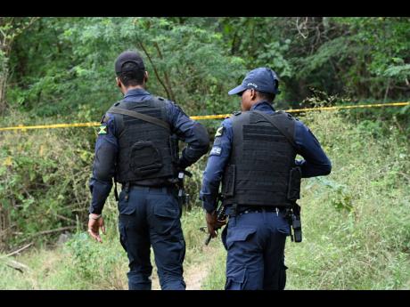 Police officers secure the scene where human remains were found in the Zambia community of Central Village, St Catherine.