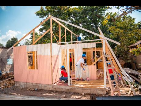 Volunteers from Food For The Poor Jamaica and the Desnoes and Geddes Foundation construct a house for Normalym Ross-Hinds at Waltham Park in St Andrew.