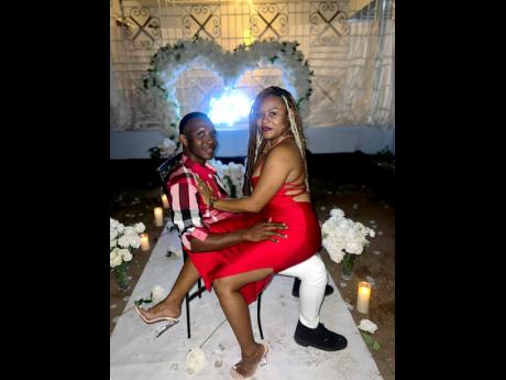 Shenice Davidson joyfully sits on the lap of her fiancé, Barrington ‘Daylight’ Heslop, moments after saying ‘yes’ to his heartfelt wedding proposal on Valentine’s Day.