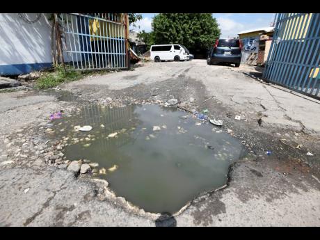 A huge pothole  entrance to the Cross Roads Market in St Andrew.
